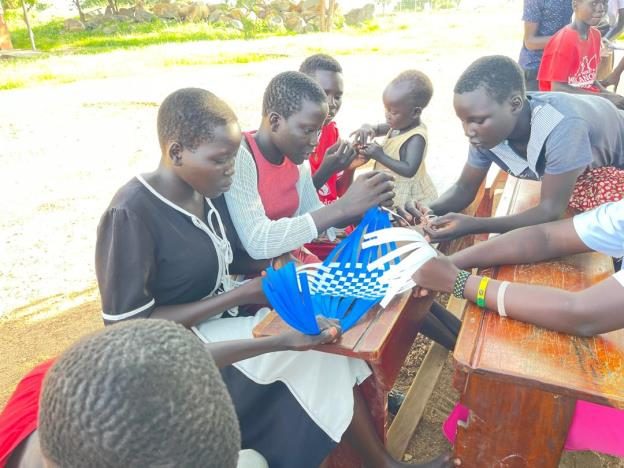 Weaving baskets with youths while educating them on early marriage